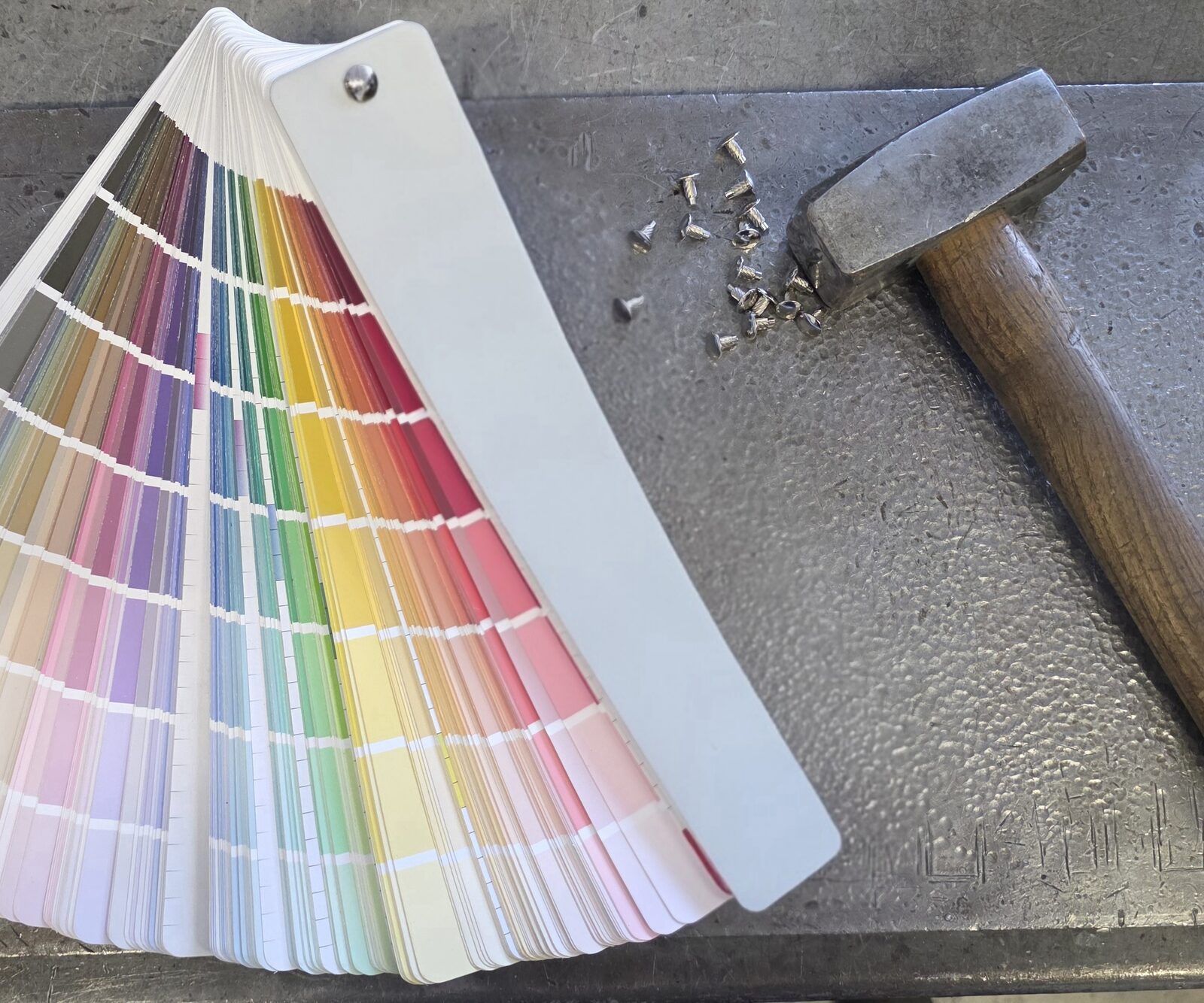 Mazzetta campionario colori e martello sul banco di lavoro a Brescia